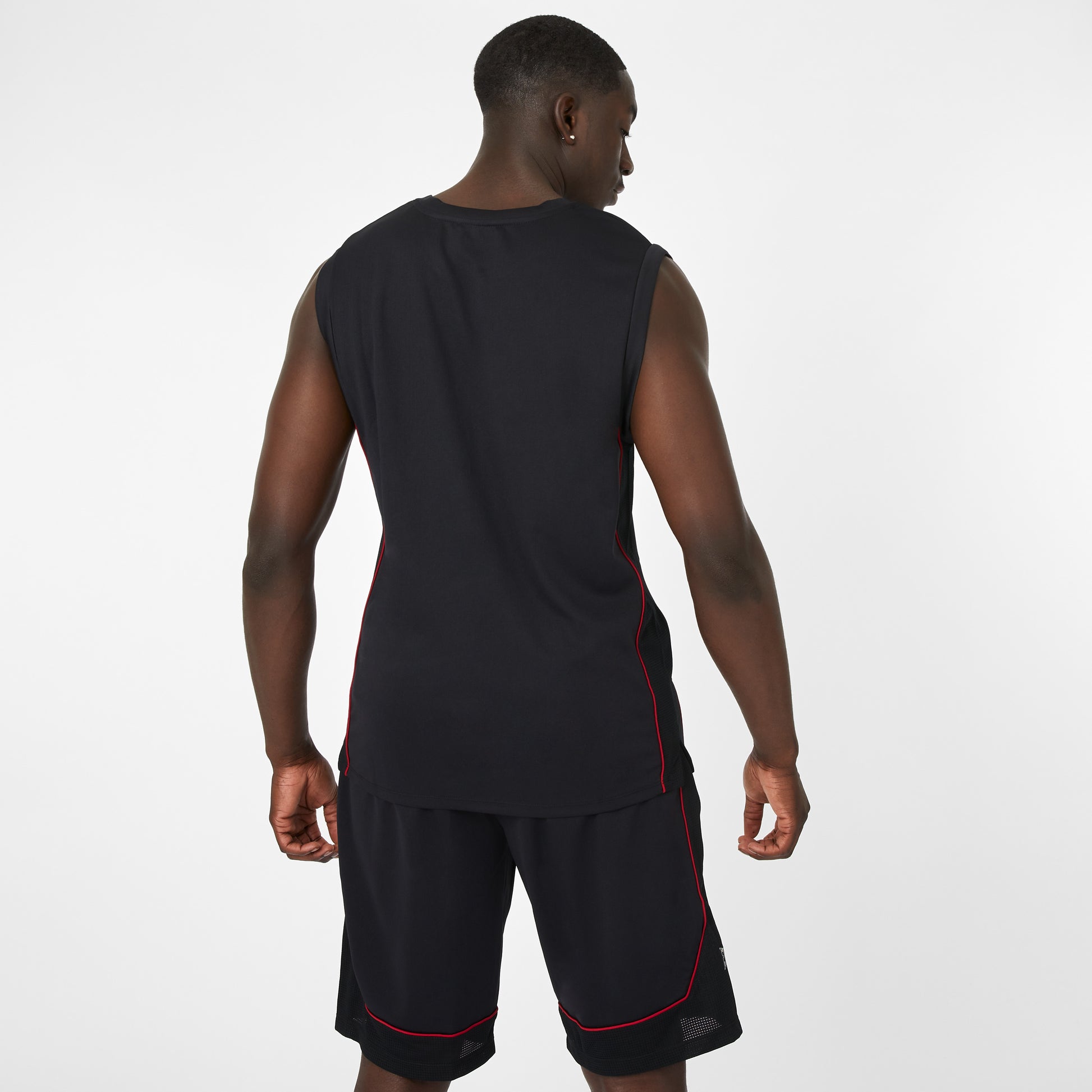 Man wearing a black sleeveless shirt and shorts with red accents on a white background