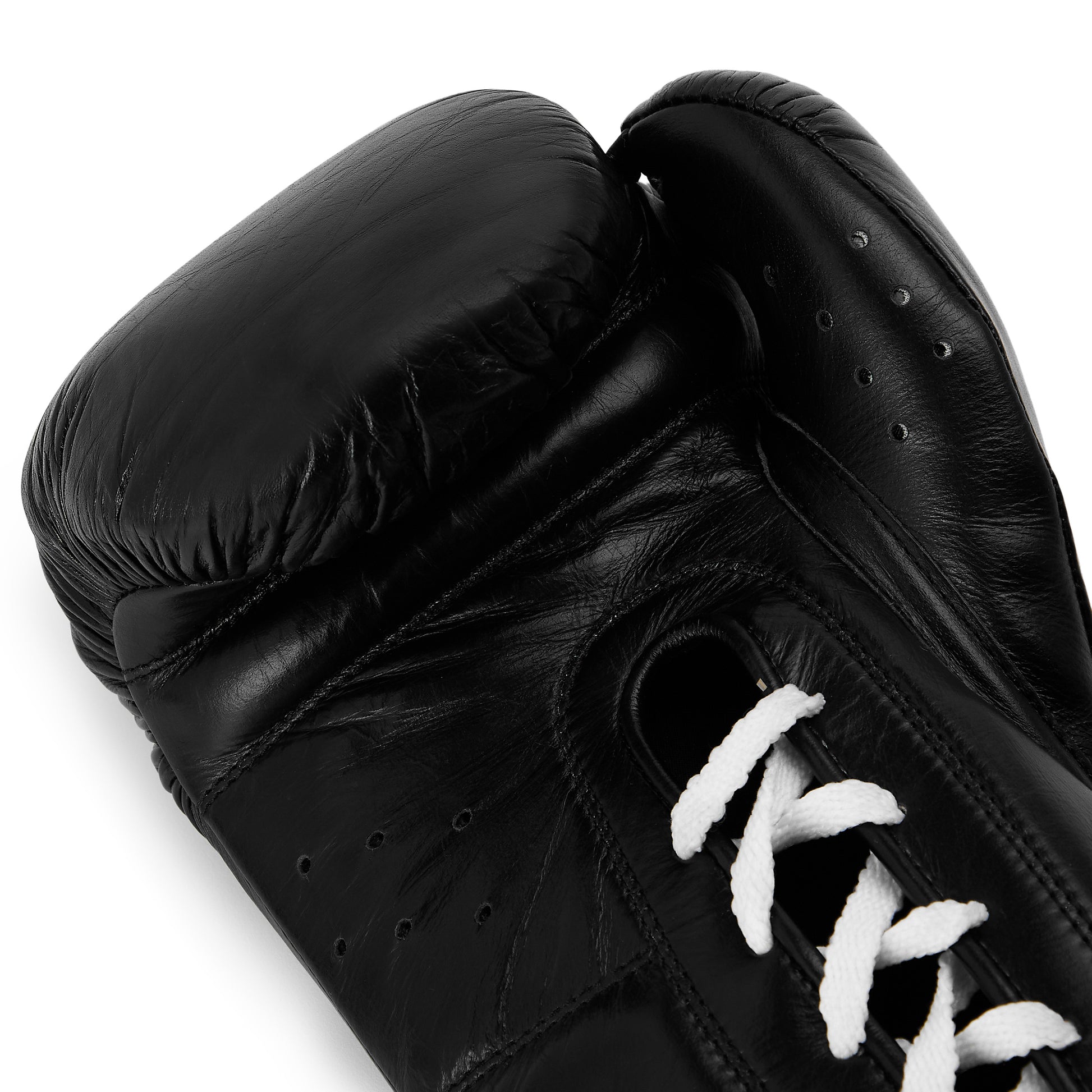 A close-up of a black leather boxing glove with wht laces, showing the padded cuff and textured leather surface against a plain background.