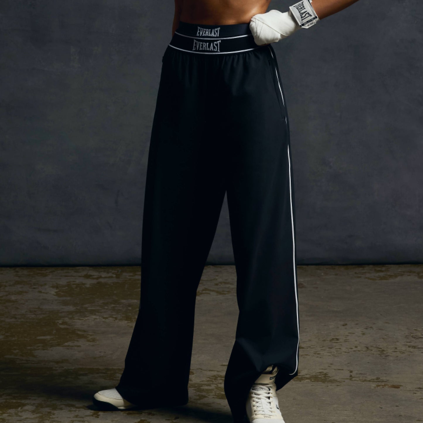 Person wearing black boxing pants with 'Everlast' branding on a dark background