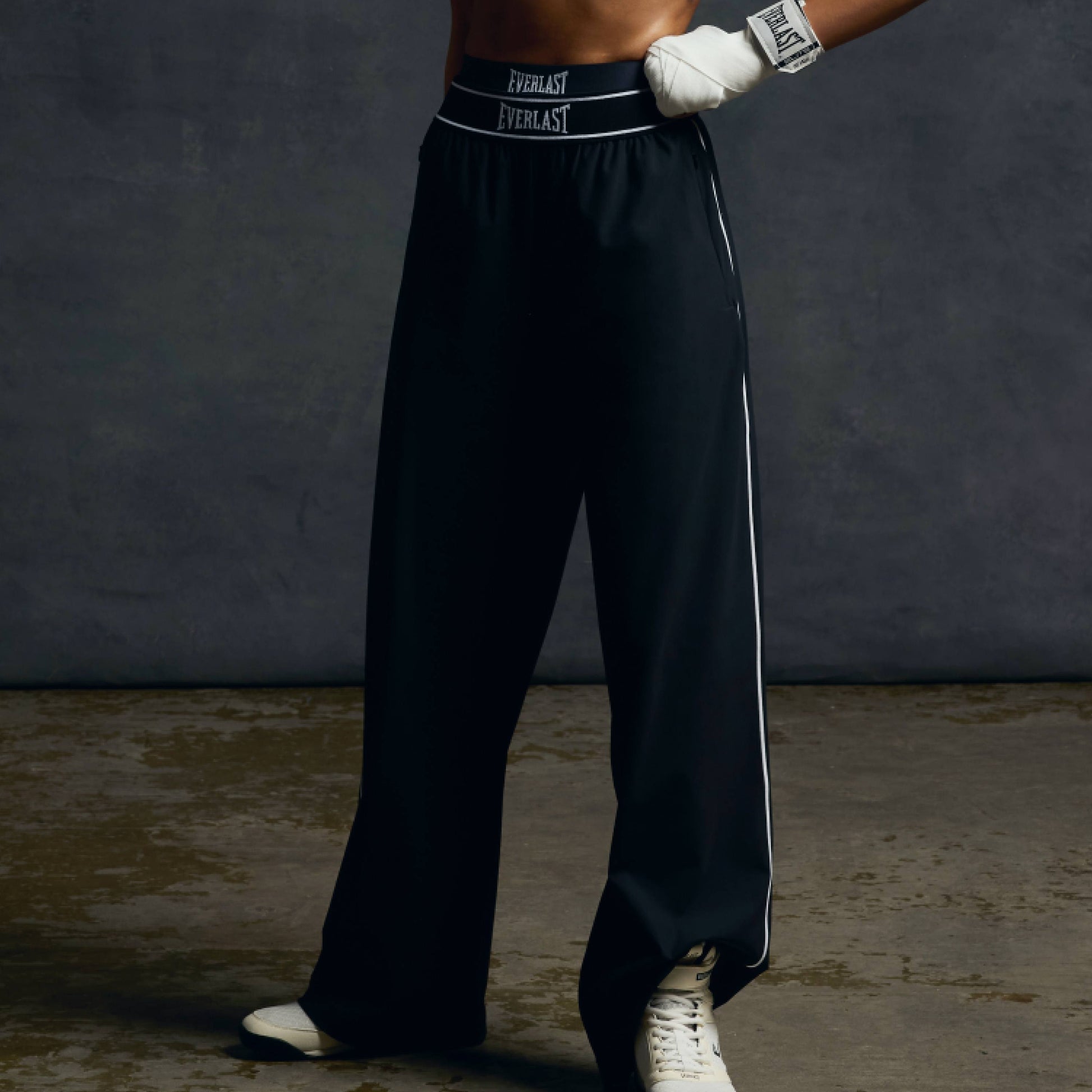 Person wearing black boxing pants with 'Everlast' branding on a dark background