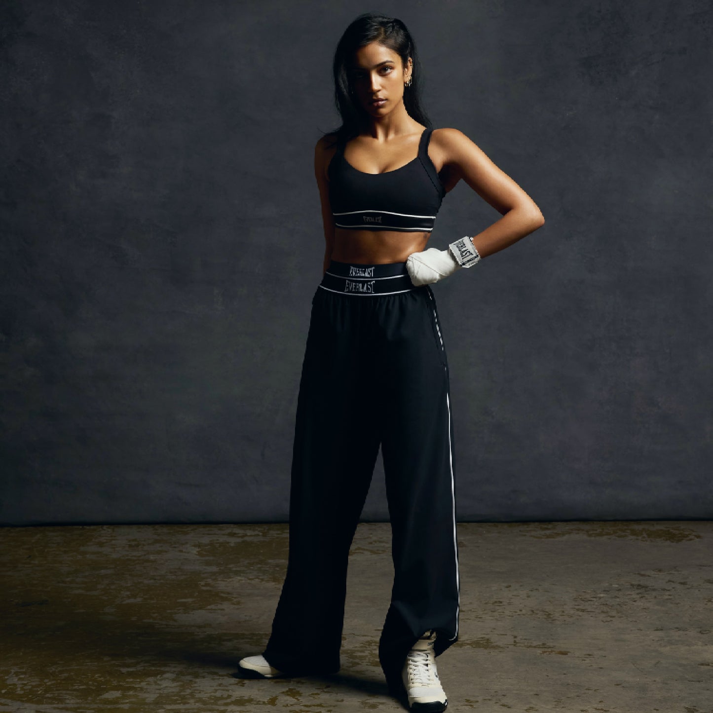 Woman in athletic wear with boxing gloves against a dark background